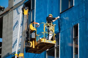 Workers on a boomlift detailing exterior of builllding